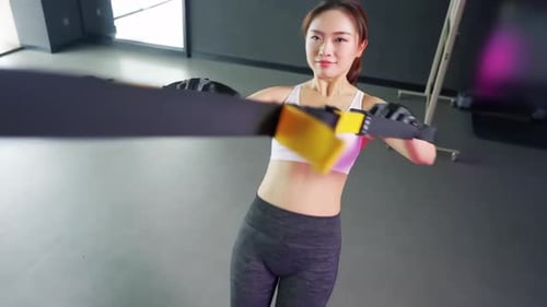 Beautiful sportswoman doing strength exercise suspension training lifting rope equipment sports gym