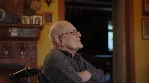 Senior Man Sitting in Wheelchair by Fireplace