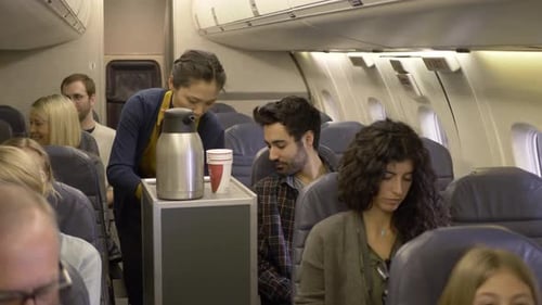 Flight attendant serving coffee to passenger on commercial airplane flight