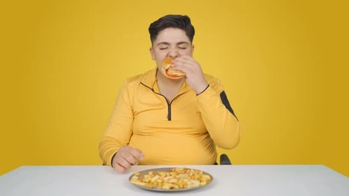 Young Adult Eating Burger and Fries at Table