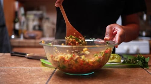 Stirring a mixture of quinoa, chopped peppers and onions for a healthy vegan homemade recipe - slow