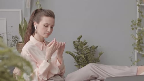Woman Checks Device While Relaxing at Desk