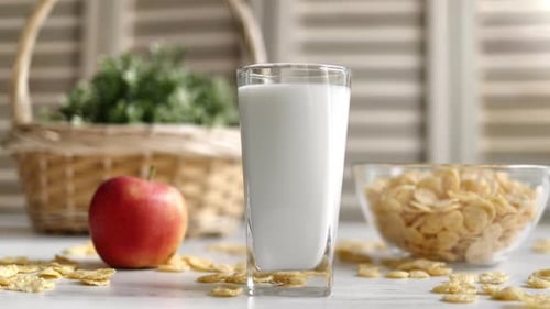 Healthy Breakfast Morning Food with Milk Corn Flakes and Apple on Rustic Kitchen Table Closeup
