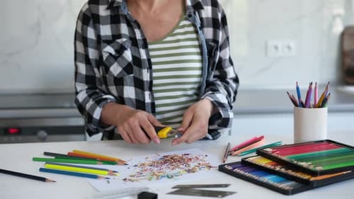 Woman Sharpening Colored Pencils at Kitchen Table