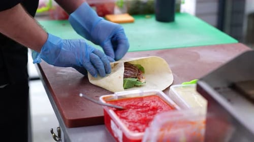 Chef Preparing a Pita Wrap with Meat and Vegetables
