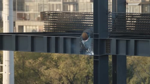 Construction Worker Welding Steel Beams on Structure
