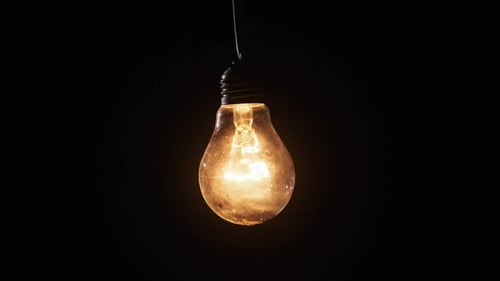 Glühlampe leuchtet und flackert auf schwarzem Hintergrund Zoom Out