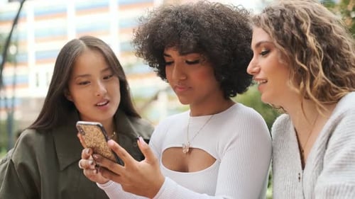 Three Friends Looking at Phone and Talking Together
