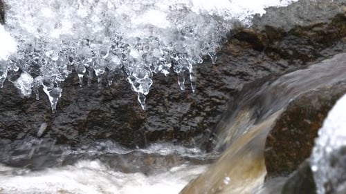 natural ice formation icicles on rock in natural stream of water