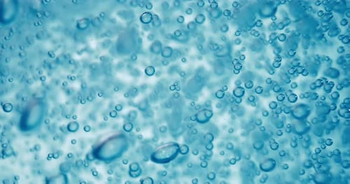Many water bubbles in blue water close up, abstract water wave with bubbles in slow motion.