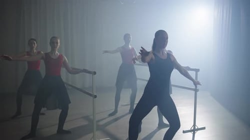 L'entraîneur montre au groupe de ballerines les bases du ballet à l'aide d'une barre
