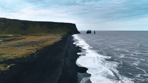 Contrasting white waves splash on the black sandy beach of volcanic origin.