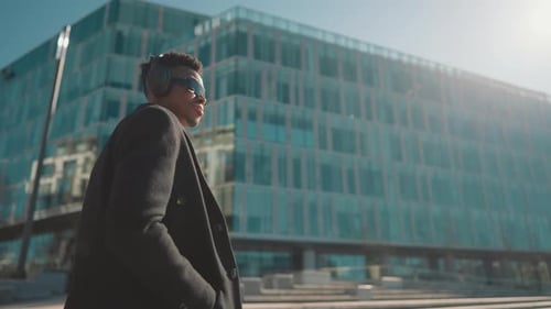 Stylish Black Man Walking Down City Street and Listening to Music By Headphones Selfconfident