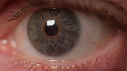 Close up of eye looking at flashing red light. extreme shot.