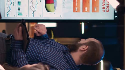 Business Meeting with Data Analysis Displayed on Screen