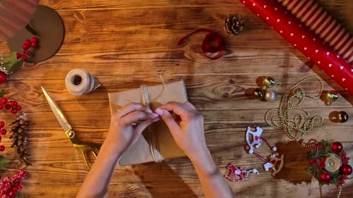 Wrapping Christmas Gift with Twine on Wooden Table