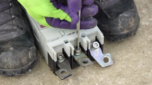 Closeup View of Electrician Installing Wires Cables Into a Electricity Power Shield Fuse Box an