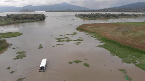 DRONE: IN TILT DOWN SHOT OF PATZCUARO LAKE WITH A BOAT AND JANITZIO ISLAND