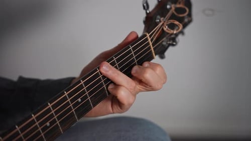 Closeup of a Man Playing an Acoustic Guitar The Frame Shows the Fretboard and the Musician's Hand