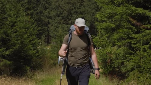 Adult Man with Backpack and Trekking Stick Walking on Green Grass in Daylight