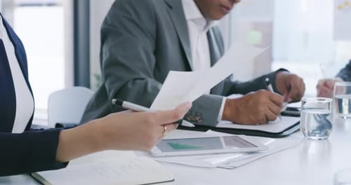 4K-Videomaterial einer Gruppe von Geschäftsleuten, die während eines Treffens in einem Büro Papierkram durchgehen