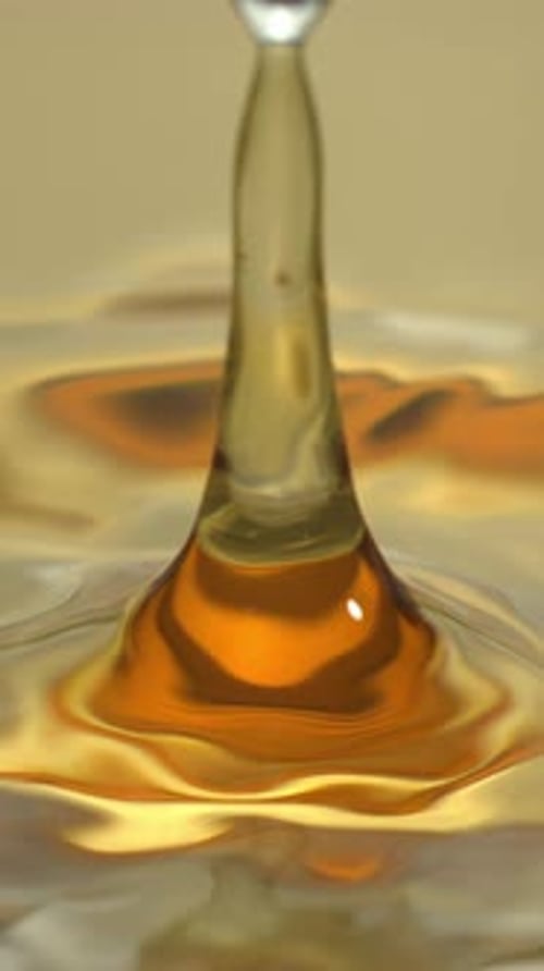 Transparent Droplet Creates Crown in Amber Liquid