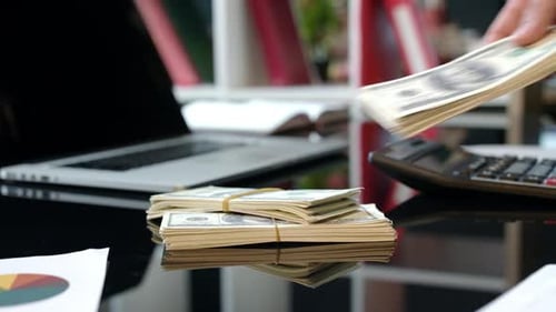 Stacks of Cash Placed on Shiny Black Desk