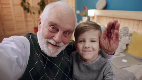 Grandfather and Grandson Smiling and Waving Indoors