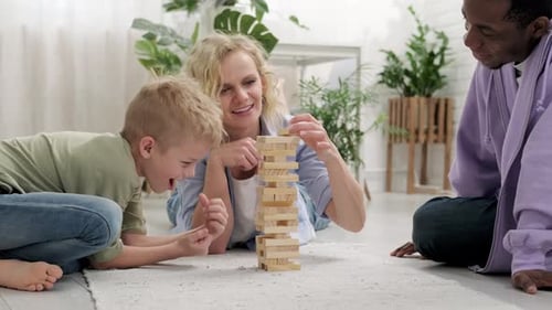 Cheerful Multiracial Family Having Fun Playing Wooden Block Tower Game Together on the Carpet at