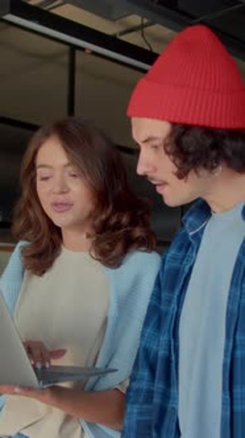 Colleagues discussing work on a laptop indoors