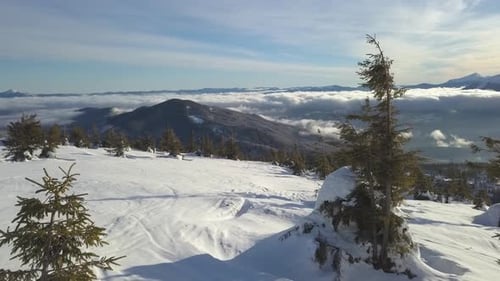 Winter landscape view of snow-covered mountains and clouds under blue sky