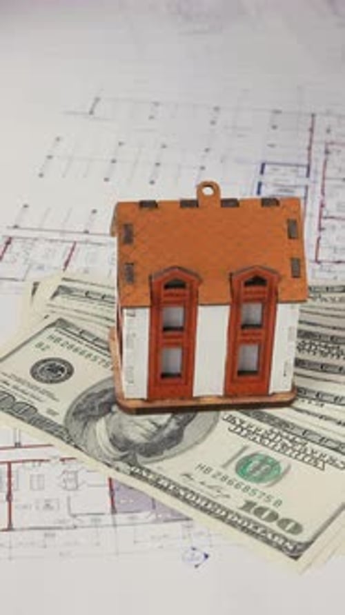 House Model on Money with Architectural Plans
