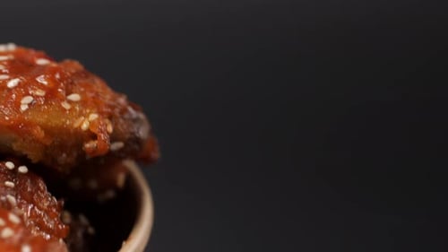 Spicy Chicken Wings Doused in Sauce Swirl in a Paper Bucket Close Up