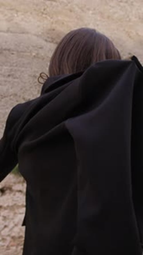 Woman Putting on Black Blazer in Urban Setting