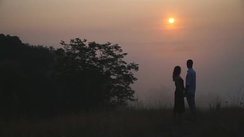 Couple Holding Hands on Hilltop at Sunrise