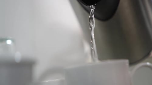 Pouring hot water into a cup, demonstrating the green tea preparation process.