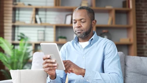 Man Using Tablet While Relaxing on Couch at Home