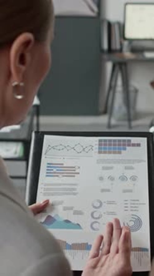 African American And Caucasian Women Analyzing Charts In Office