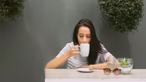 Woman enjoys hot beverage at table in cafe