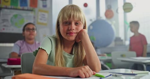 Beautiful Elementary School Girl Sitting at the Desk Smiling and Looking at Camera