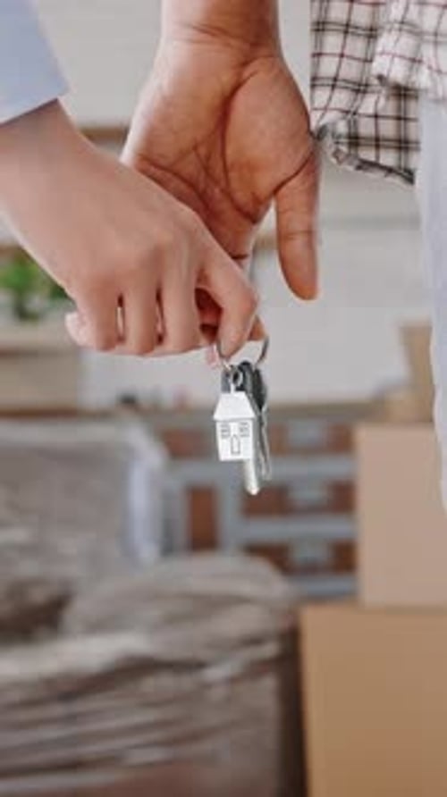 Cropped View of a Couple Holding Hands and Key to New Home Moving in Together Real Estate Concept