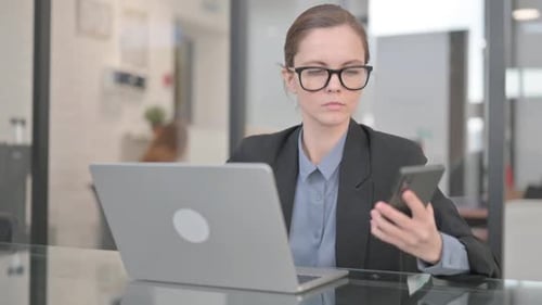 Woman Uses Smartphone and Laptop in Office