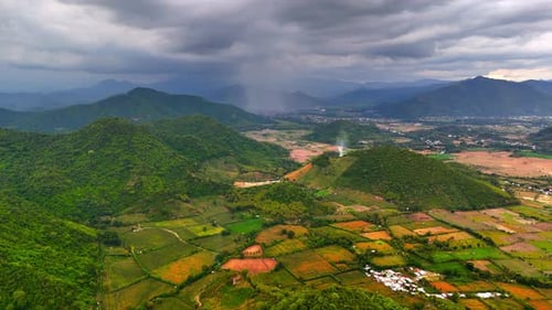 Dramatic storm clouds over mountain valley and patchwork farmlands aerial drone view