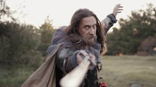 Man in Armor Points Sword at Camera