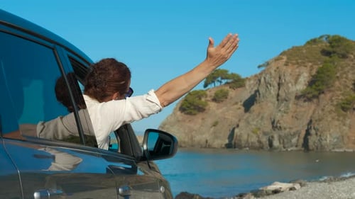 Woman Enjoying Road Trip Waving Out Car Window