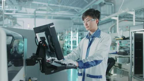 On High Tech Factory Asian Engineer Uses Computer for Programming Pick and Place Surface Mount Elec