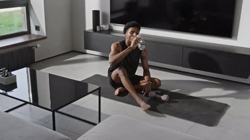 Athletic Man Drinking Water on Exercise Mat at Home