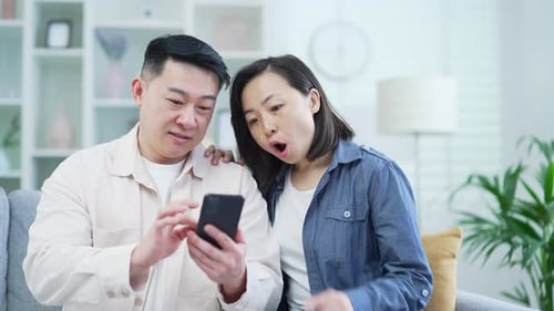 Couple Using Smartphone Together on Sofa at Home