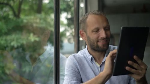 Man Using Tablet Device by Window Indoors