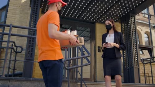Delivery Man in Mask Handing Over Order to Protected Face Businesswoman Outdoors